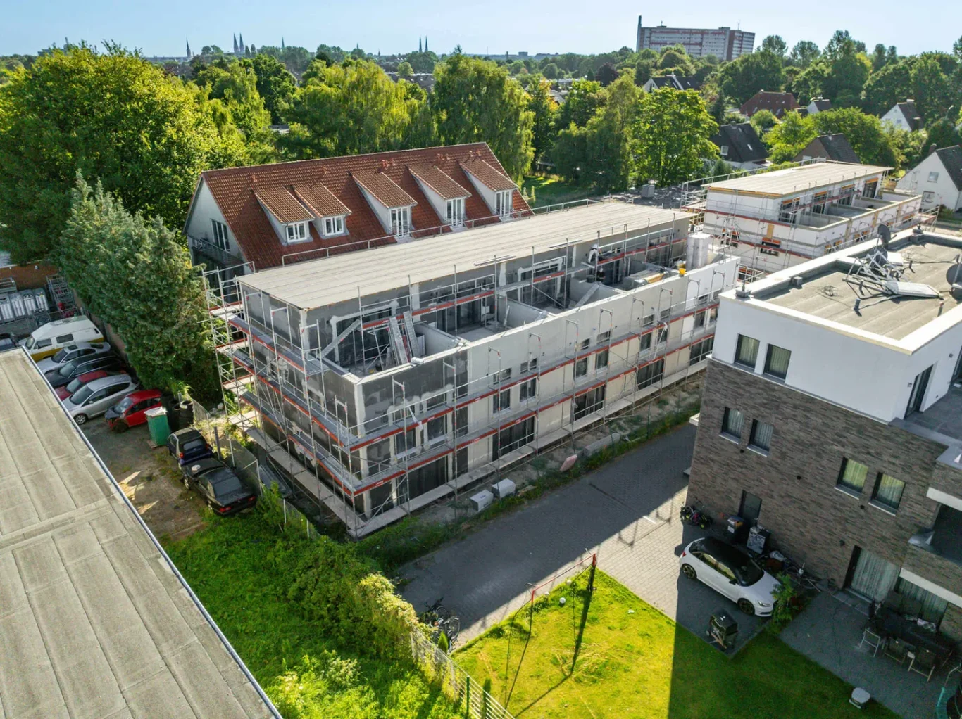 Neues Mehrfamilienhaus mit Grünflächen und angrenzenden Wohngebäuden.