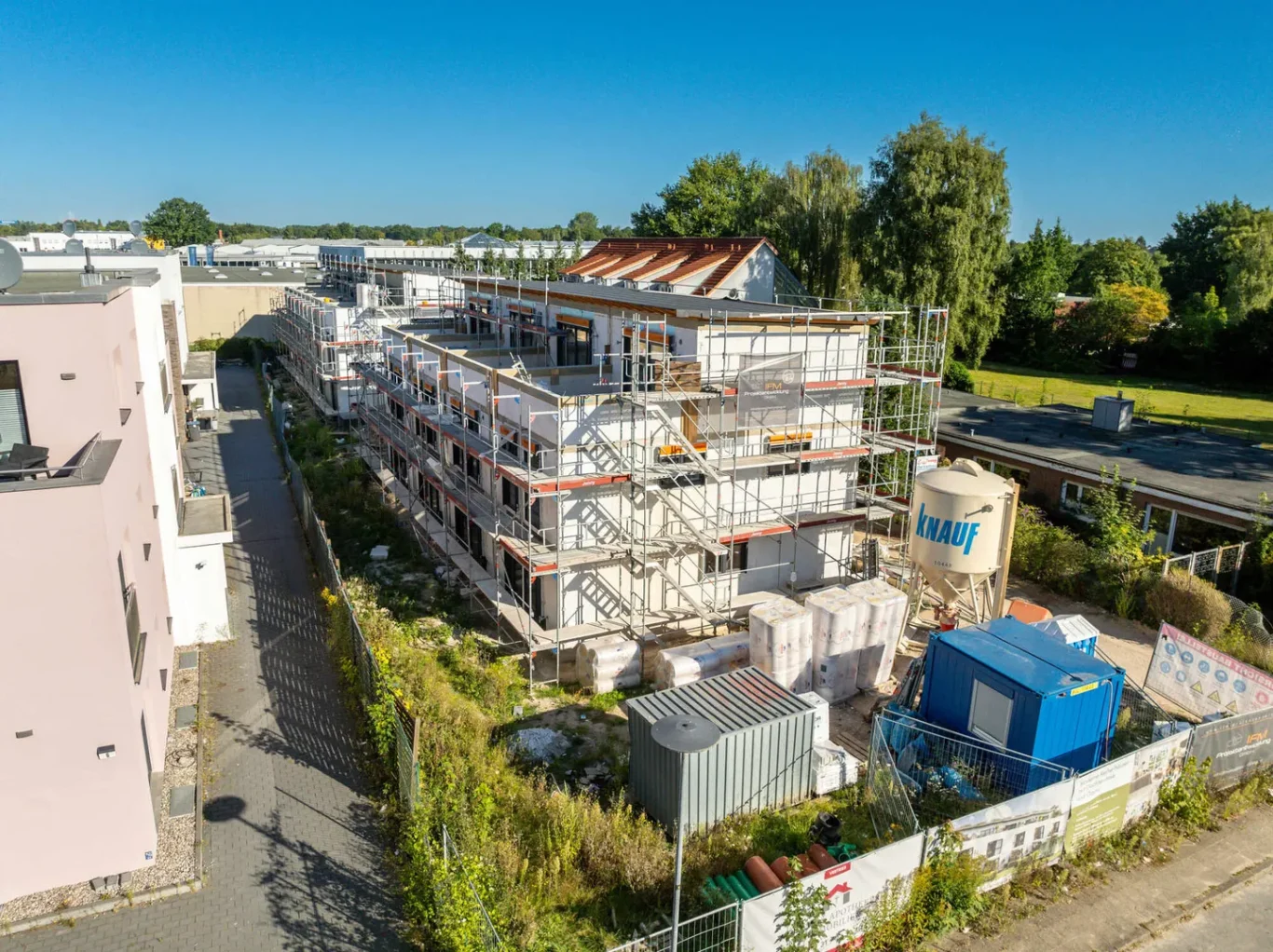 Bauprojekt mit mehreren Etagen, Rohbau und Baustellenmaterialien in der Umgebung.