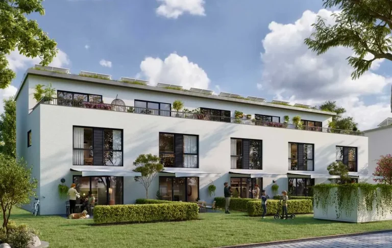 Moderne Wohnanlage mit weißen Fassaden und begrünten Terrassen unter einem blauen Himmel.