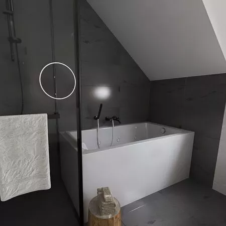 Modernes Badezimmer mit freistehender Badewanne und grauen Wänden. Handtuch hängt an der Wand.